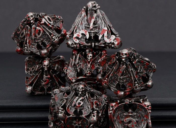 Image of metallic dnd dice featuring hollow skulls and angel wings, with blood spatters across panels