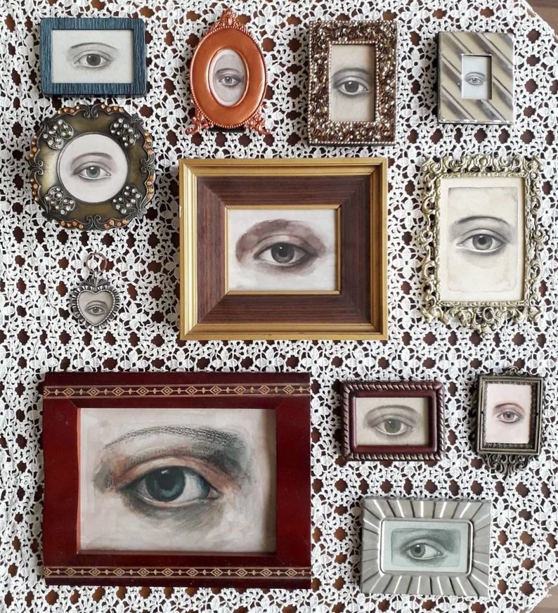 a photo of a collection of small framed paintings of eyes