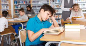 image of a white middle school boy reading in a library