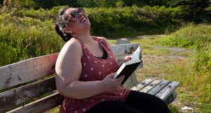 Image of a fat woman reading and laughing outside