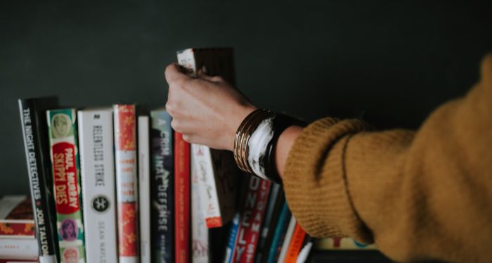 a hand selecting a book of a shelf