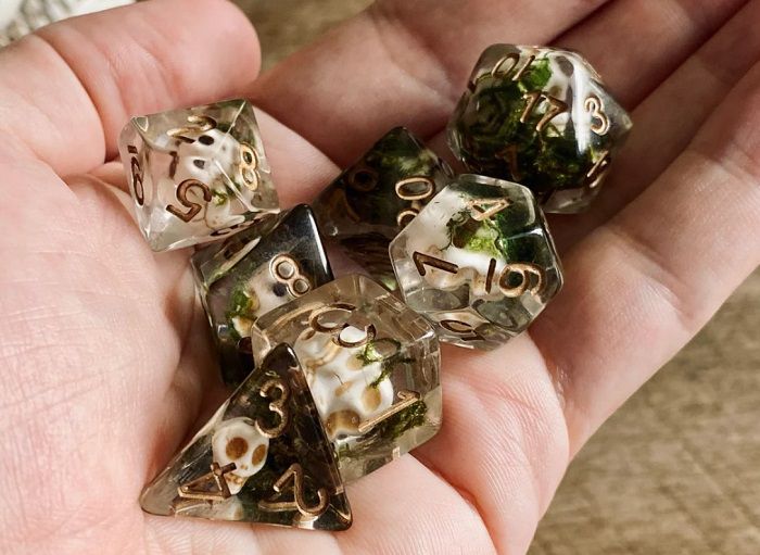 Image of clear resin dnd dice set featuring small undead skulls with brown numbers