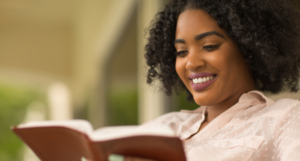a photo of a Black woman smiling while reading