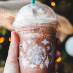 a photo of someone holding a starbucks cup up to a Christmas tree